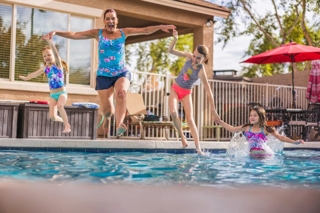 woman jumps into the pool to play with children