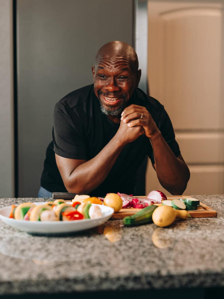 man smiles while preparing the meal
