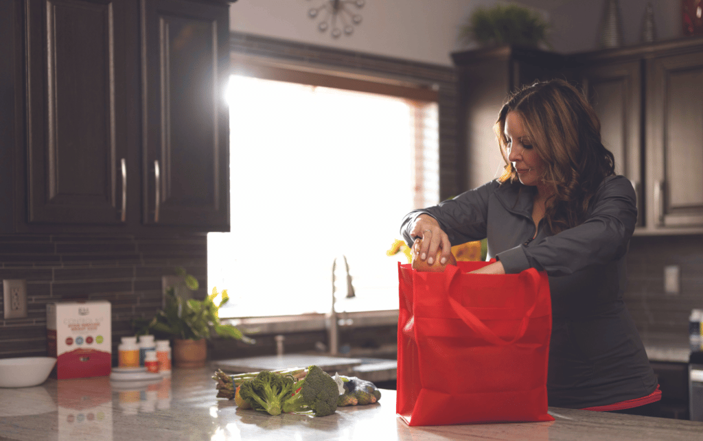 A woman unpacks groceries in a kitchen.