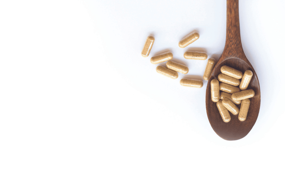 Brown capsules sit on a spoon.